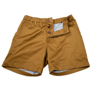 A pair of mustard yellow shorts with buttoned waist and patterned pocket lining visible, designed for bulge enhancement, laid flat on a white background.