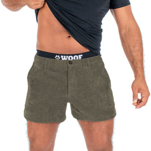 A guy lifting up his dark t-shirt to show green shorts and a black waistband with a bulge enhancement. Only his torso and legs are visible.