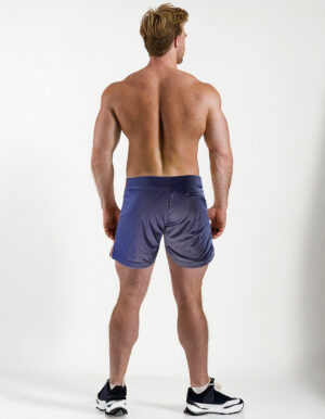 Back view of a muscular guy with blond hair, wearing WOOF Freeball Mesh Field Shorts in Navy and black sneakers, standing against a white background.